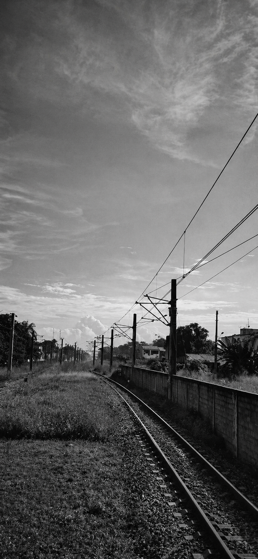 Trilhos de trem em preto e branco seguindo em direção ao horizonte