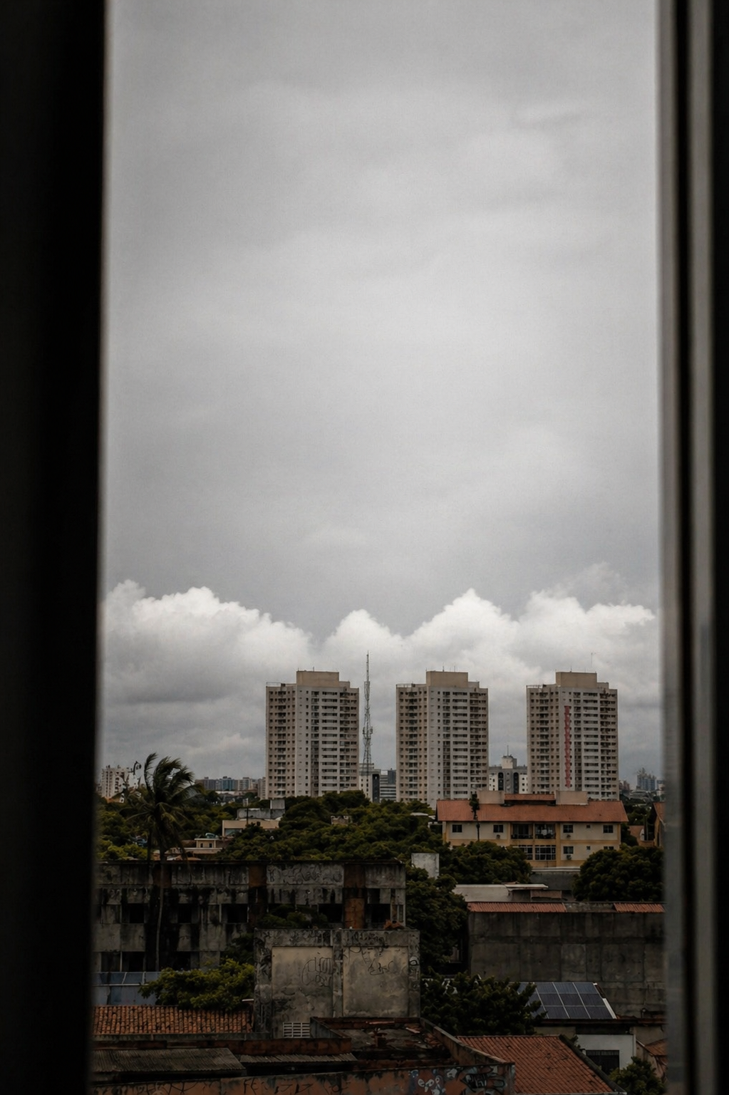 Cidade vista por uma fresta ou janela escura, com prédios ao fundo